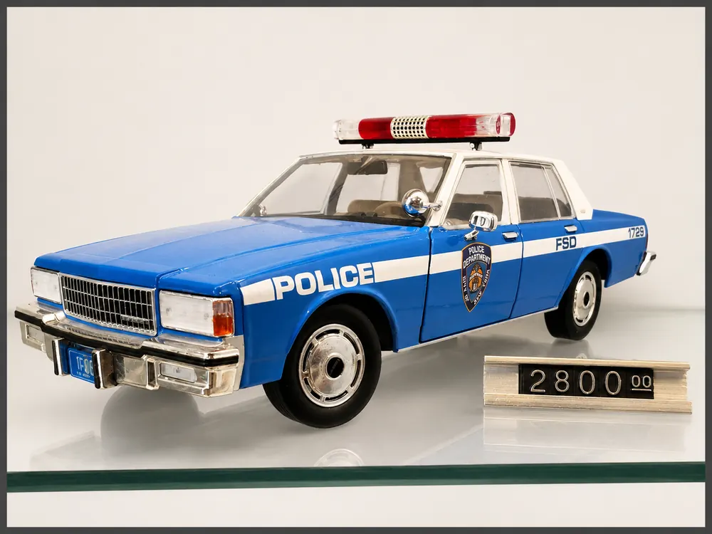 Patrulla azul y blanca, fotografiada en la vitrina de Automovilia