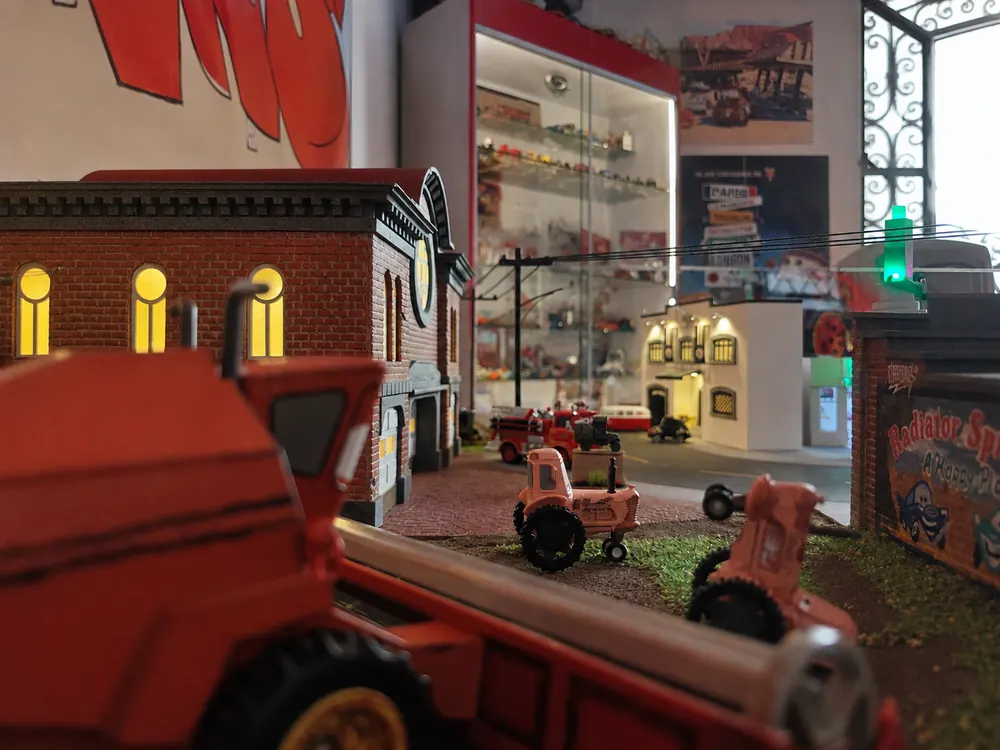 Detalle del tractor rojo en primer plano con el taller del pueblo detrás