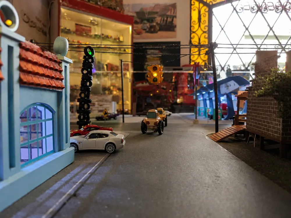 Calle principal del diorama vista a ras de suelo, con los coches estacionados frente a los locales